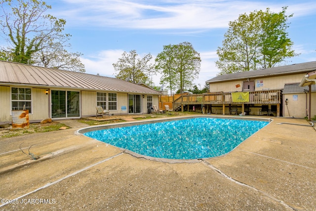 view of swimming pool with a fenced in pool, a wooden deck, and a patio