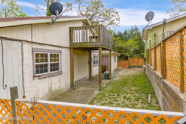 exterior space with a lawn, a wooden deck, fence private yard, central AC, and stucco siding