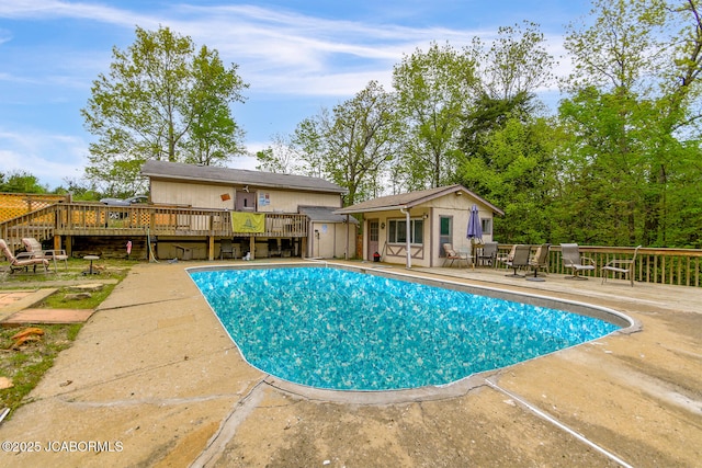 view of swimming pool featuring a patio, a fenced in pool, a wooden deck, and an outbuilding