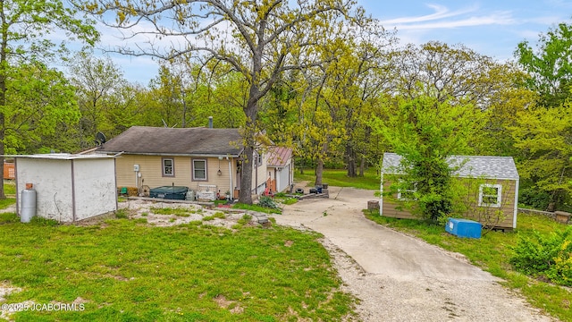 back of house with a storage shed, an outdoor structure, and a yard