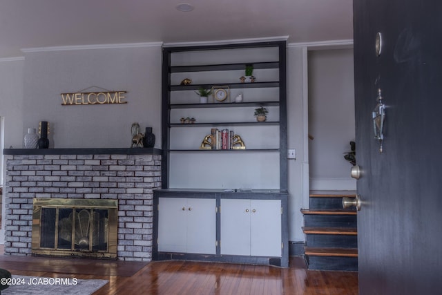 unfurnished living room featuring built in shelves, dark wood-type flooring, and a brick fireplace