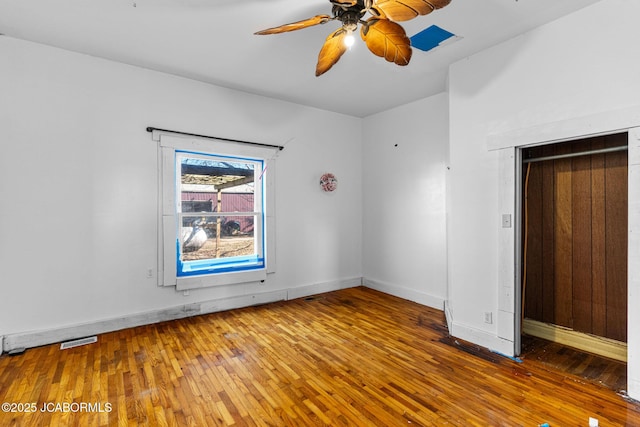 spare room featuring ceiling fan, hardwood / wood-style flooring, visible vents, and baseboards