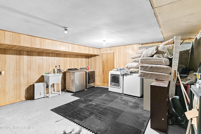 washroom with a sink, laundry area, wooden walls, and washer and dryer