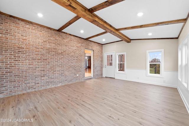 unfurnished living room with vaulted ceiling with beams, light hardwood / wood-style flooring, and brick wall