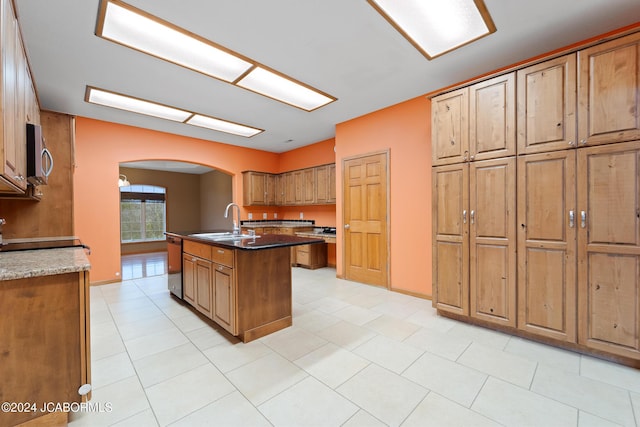 kitchen featuring sink, stainless steel appliances, dark stone counters, and an island with sink