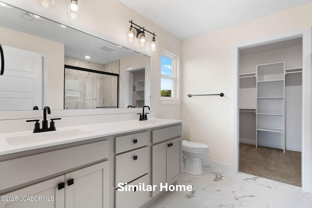 bathroom with marble finish floor, a stall shower, a sink, and a walk in closet