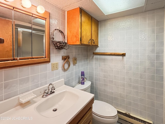 bathroom with vanity, a baseboard heating unit, toilet, tile walls, and a shower with shower door