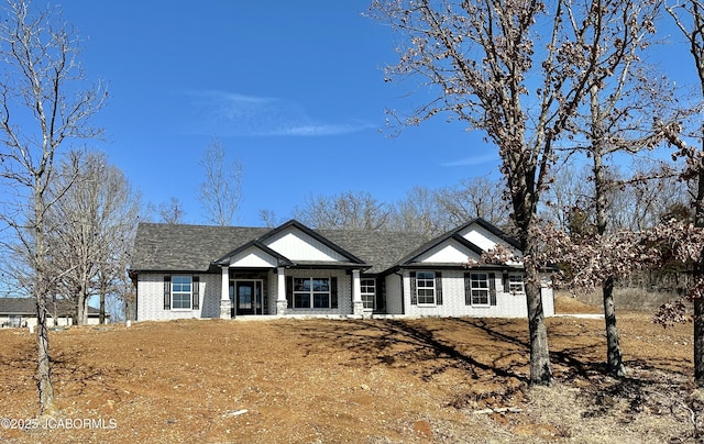 view of front facade with brick siding, an attached garage, and roof with shingles