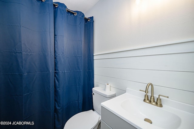 bathroom featuring a shower with shower curtain, vanity, and toilet