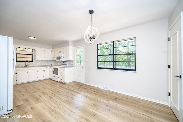 kitchen featuring white appliances, an inviting chandelier, white cabinets, sink, and decorative light fixtures