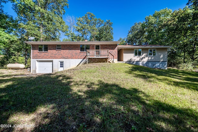 rear view of house featuring a lawn, a wooden deck, and a garage