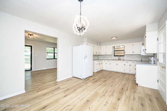 kitchen with white cabinetry, backsplash, a chandelier, pendant lighting, and white appliances