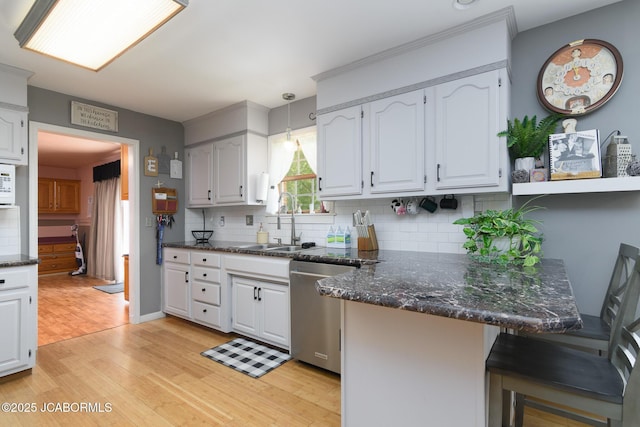 3609 Shamrock Rd, Jefferson City, MO 65101 - kitchen featuring stainless steel dishwasher, a peninsula, light wood-style floors, and backsplash