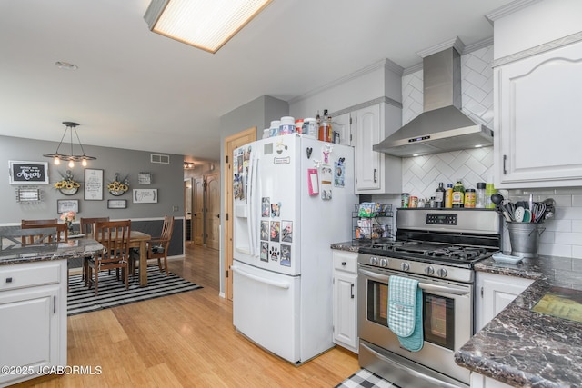 3609 Shamrock Rd, Jefferson City, MO 65101 - kitchen featuring wall chimney range hood, white fridge with ice dispenser, stainless steel range with gas stovetop, light wood-type flooring, and white cabinetry