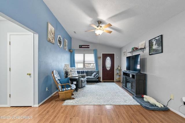 living room featuring a ceiling fan, lofted ceiling, wood finished floors, and baseboards