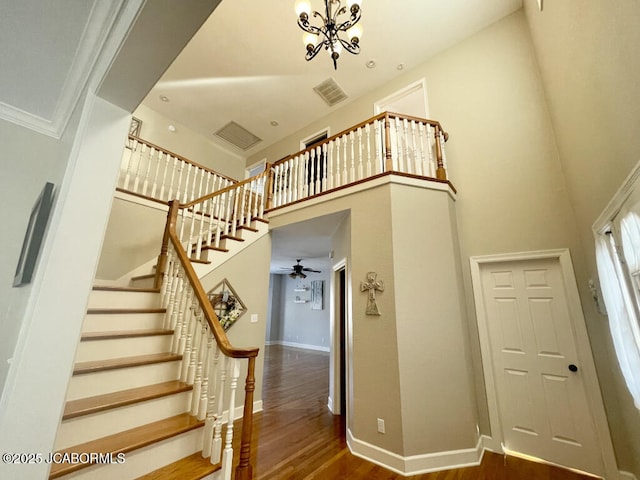 stairs with an inviting chandelier, wood-type flooring, and a high ceiling
