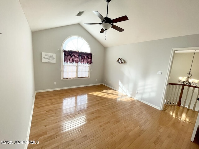 spare room with ceiling fan with notable chandelier, vaulted ceiling, and light wood-type flooring