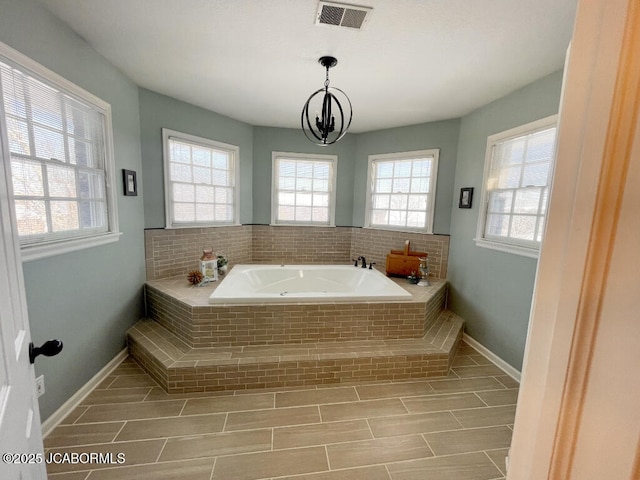 bathroom with a relaxing tiled tub and plenty of natural light