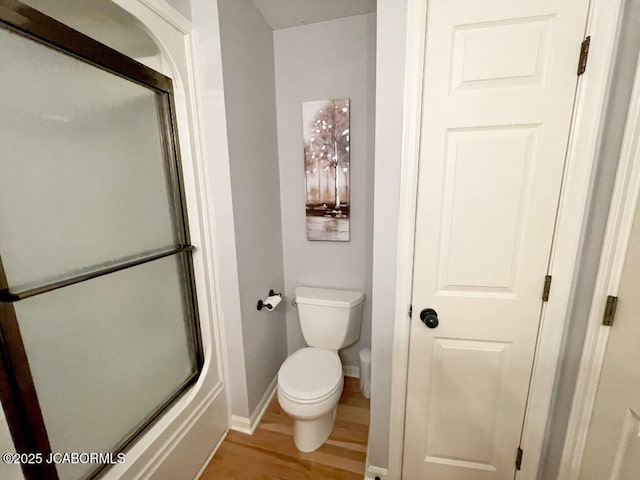 bathroom with toilet, hardwood / wood-style floors, and a shower with shower door
