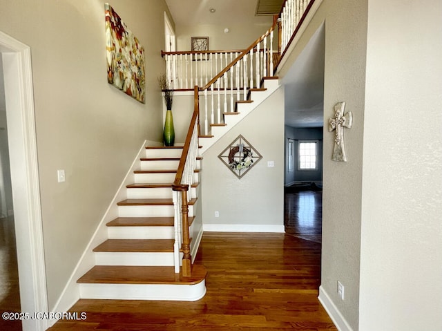 stairs featuring hardwood / wood-style flooring and a high ceiling