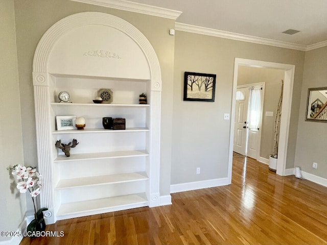 interior details featuring crown molding, built in shelves, and hardwood / wood-style floors