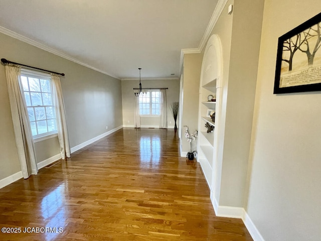 interior space featuring built in shelves, ornamental molding, and wood-type flooring