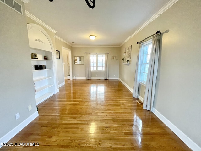 interior space with hardwood / wood-style flooring, ornamental molding, and built in shelves