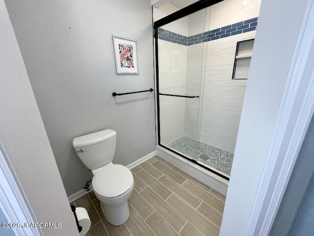 bathroom featuring a shower with shower door and toilet