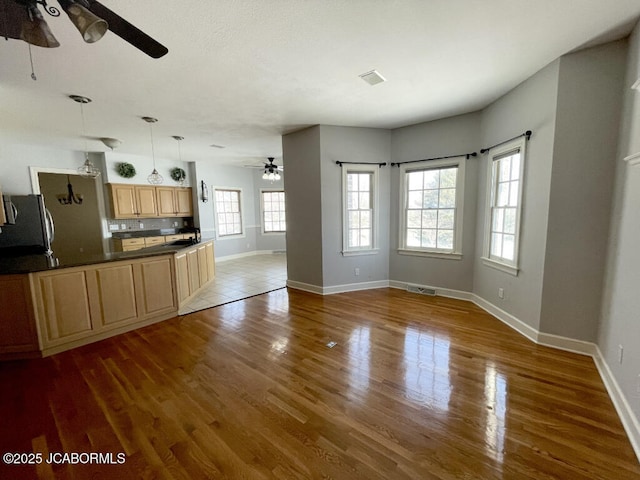 unfurnished living room featuring dark wood-type flooring and ceiling fan