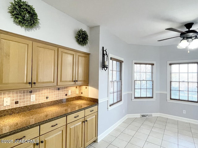 kitchen featuring decorative backsplash, light brown cabinets, dark stone counters, and light tile patterned flooring