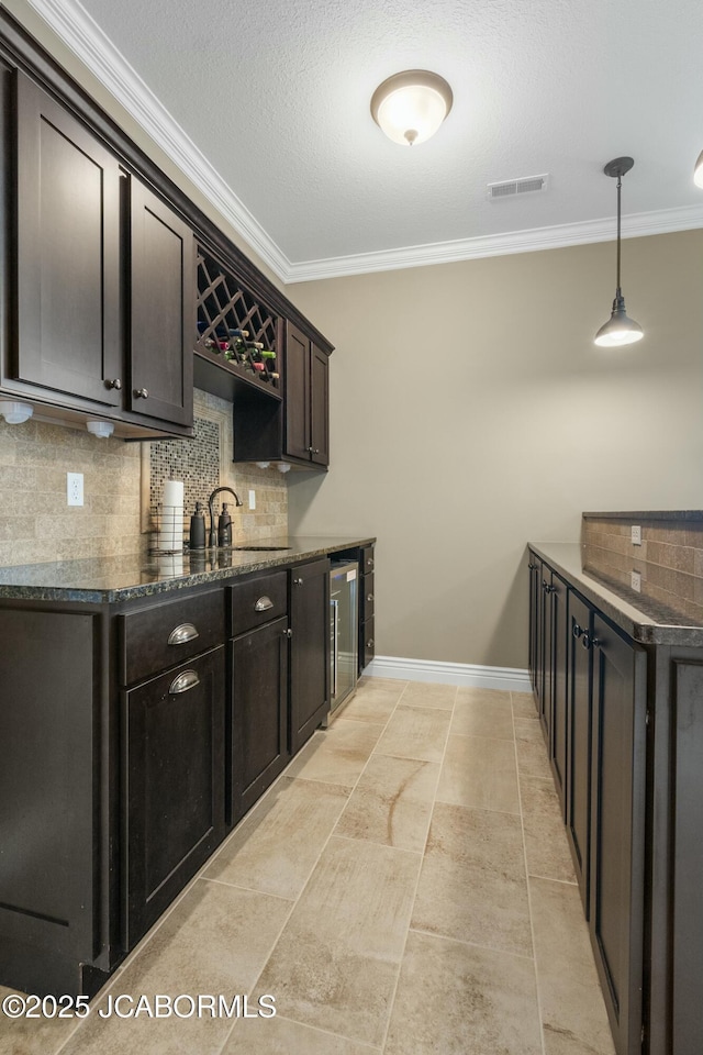bar featuring crown molding, a sink, beverage cooler, baseboards, and backsplash