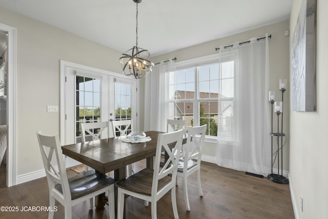 dining area featuring dark wood finished floors, a notable chandelier, a wealth of natural light, and baseboards