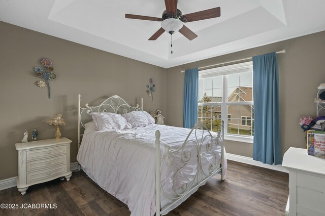 bedroom featuring dark wood finished floors, baseboards, a ceiling fan, and a tray ceiling