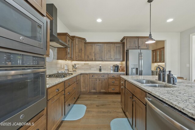 kitchen featuring tasteful backsplash, light wood-style flooring, light stone counters, stainless steel appliances, and a sink