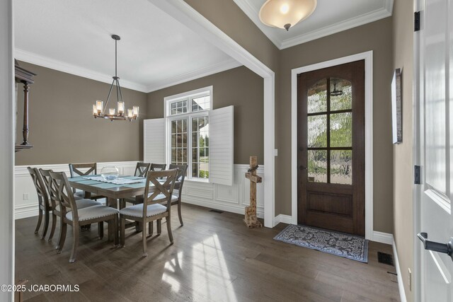 foyer featuring an inviting chandelier, dark wood-style flooring, plenty of natural light, and ornamental molding