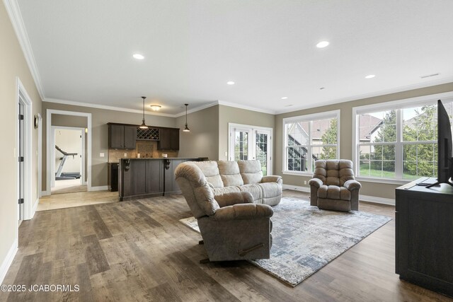 living room featuring wood finished floors, crown molding, and baseboards