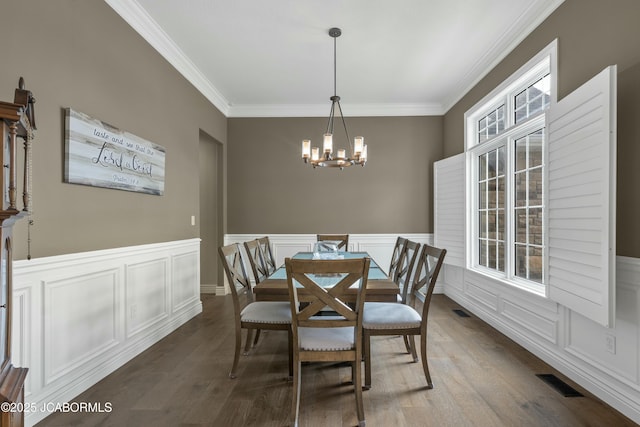 dining room with visible vents, a wainscoted wall, an inviting chandelier, ornamental molding, and wood finished floors