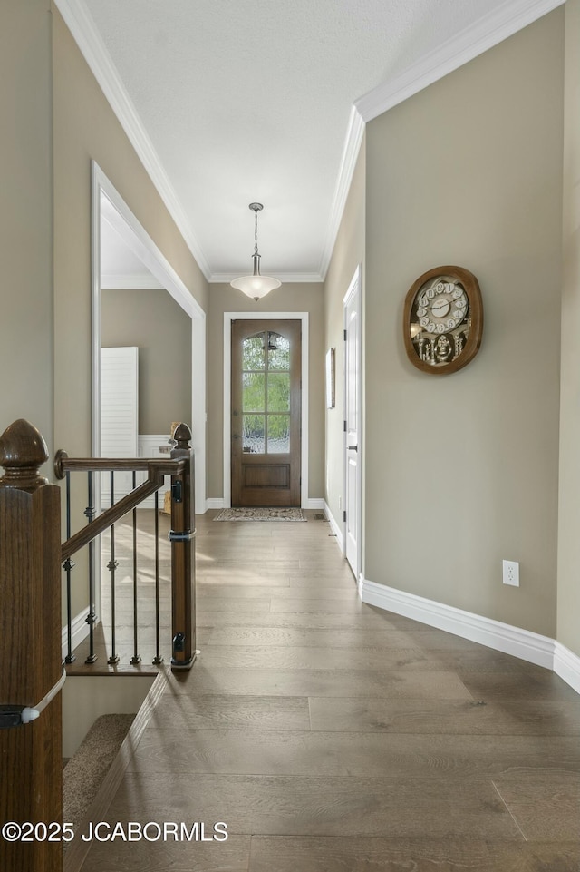 foyer entrance with wood finished floors, crown molding, and baseboards