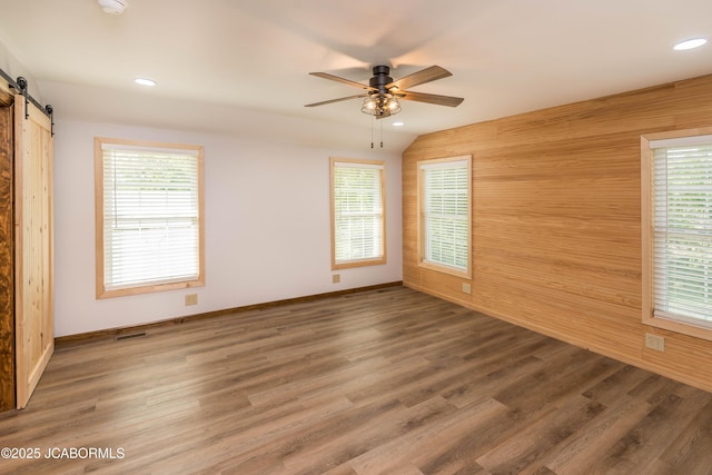 7515 Rte M, Jefferson City, MO 65101 - empty room with a barn door, a ceiling fan, plenty of natural light, wood walls, and wood finished floors