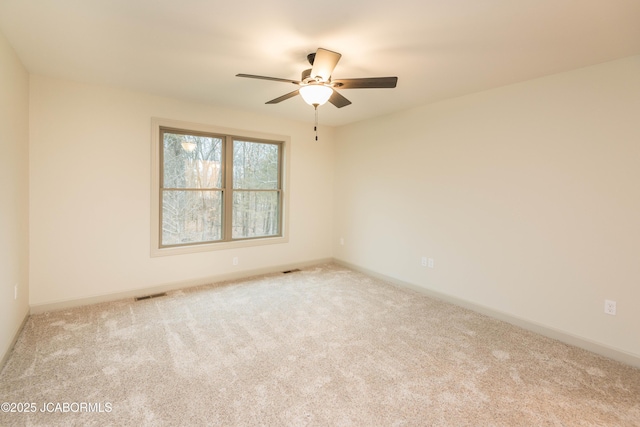 unfurnished room with a ceiling fan, light carpet, and baseboards