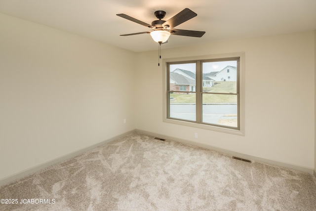 spare room featuring light carpet, ceiling fan, visible vents, and baseboards