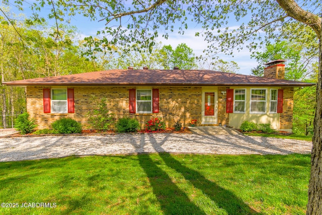 ranch-style house with brick siding, a chimney, and a front lawn