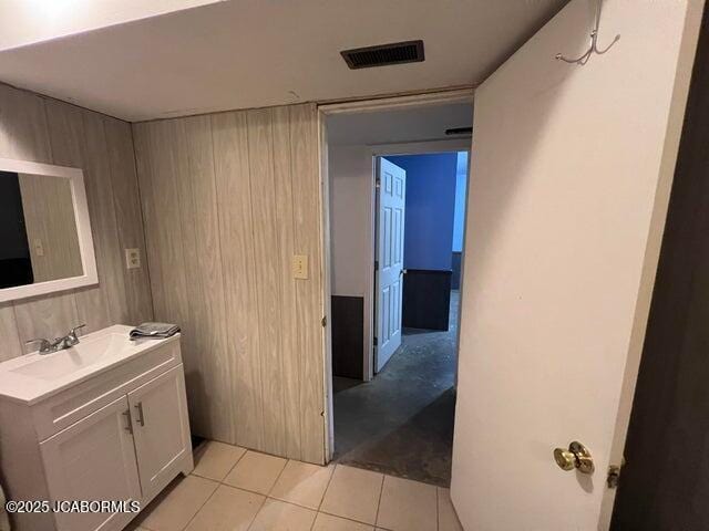 bathroom featuring tile patterned flooring, vanity, and wooden walls