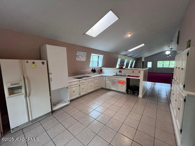 5888 State Rd E, Auxvasse, MO 65231 - kitchen featuring white fridge with ice dispenser, lofted ceiling, a skylight, light tile patterned floors, and light countertops