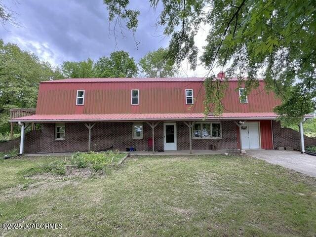 view of front of property featuring a front lawn, metal roof, and brick siding