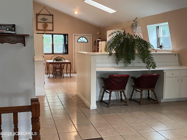 5888 State Rd E, Auxvasse, MO 65231 - kitchen featuring light tile patterned floors, a skylight, healthy amount of natural light, light countertops, and vaulted ceiling