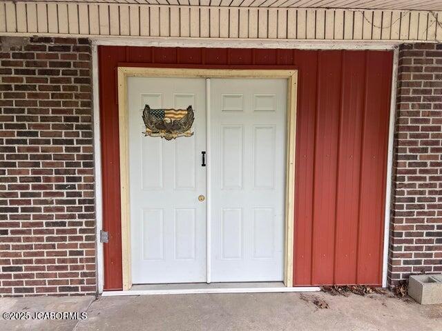 doorway to property with brick siding and board and batten siding