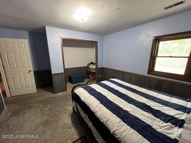 bedroom featuring wainscoting and wooden walls