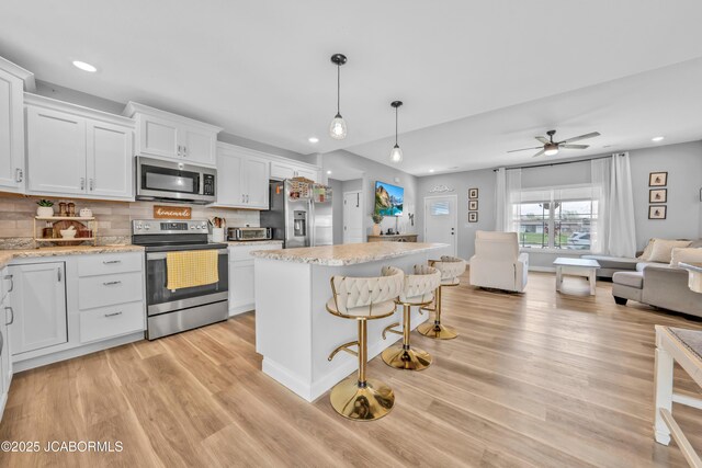 15250 General Dr, Ashland, MO 65010 - kitchen with appliances with stainless steel finishes, white cabinets, backsplash, light wood finished floors, and open floor plan