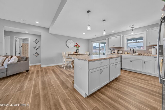 15250 General Dr, Ashland, MO 65010 - kitchen with decorative backsplash, white cabinets, light wood finished floors, a sink, and a center island